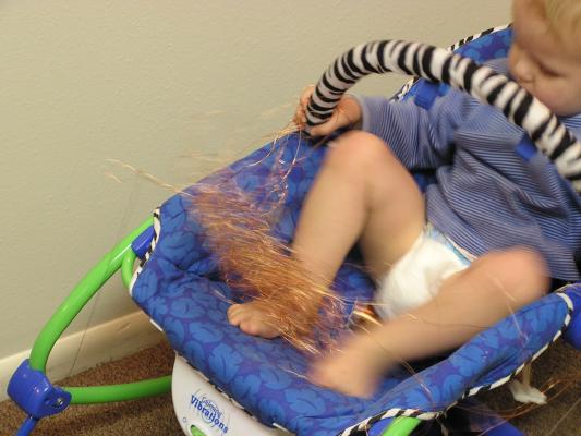 Noah plays with some copper wire in the baby chair.