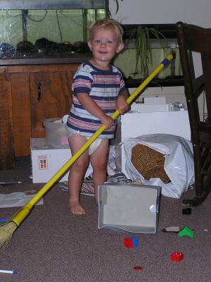 Noah sweeps up some toys.