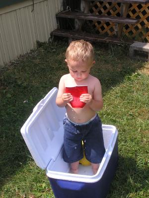 Noah plays with water and a red cup.