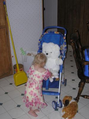 Sarah plays with a white bear in the stroller.
