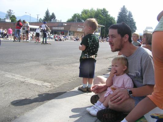 Sweet Pea Festival Parade. Sarah eats some candy  on David's lap. Noah watches.