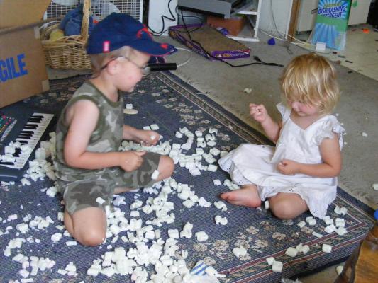 Noah and Sarah play with a box of styrofoam peanuts