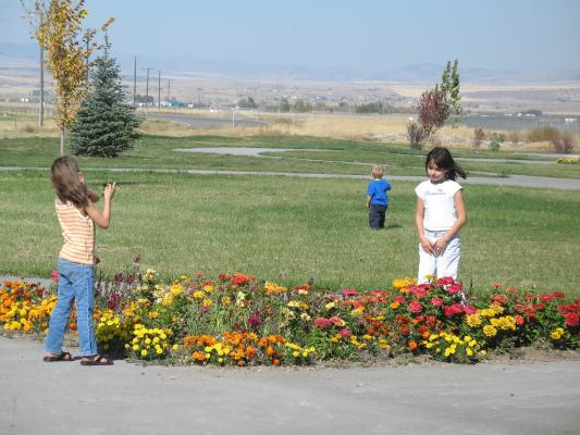 Andrea, Noah and Malia play by the flowers.