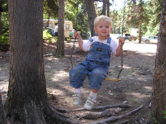 Noah sits on a swing at church camp.