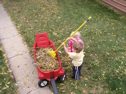 Sarah and Noah play with leaves in the wagon.