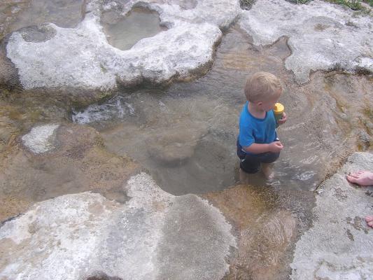 Noah wades in a limestone pool.