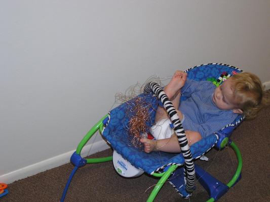 Noah plays with some copper wire in the baby chair.
