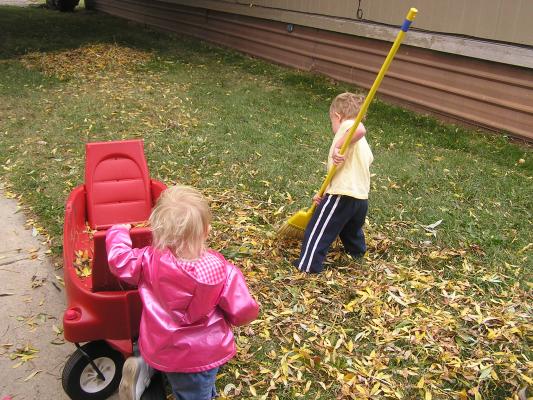Sarah and Noah play with leaves in the wagon.