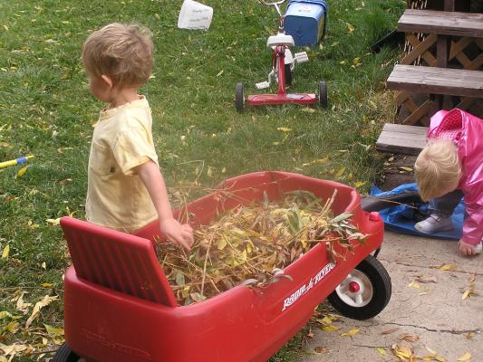Noah and Sarah play with leaves in the wagon.