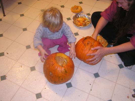 Sarah and her mom scoop out pumpkins.