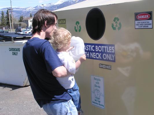 Noah puts a plastic milk jug into the recycling container.