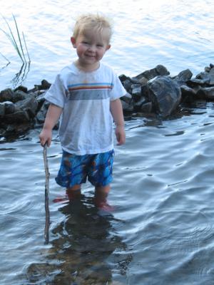 Noah plays in the lake by the rock bridge.