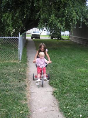Andrea helps Sarah ride a trike.