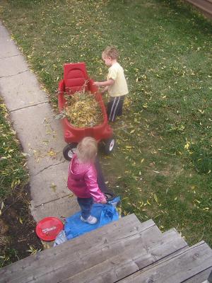 Noah and Sarah play with leaves in the wagon.