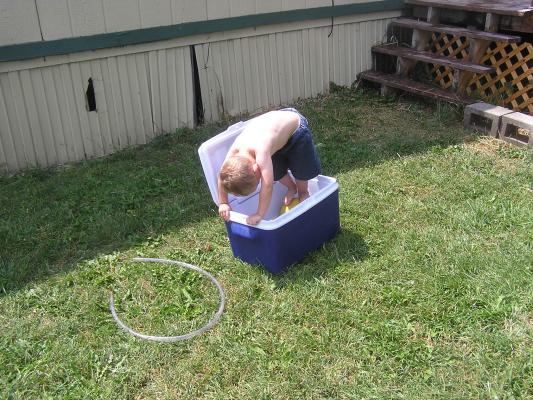 Noah plays in the cooler filled with water.