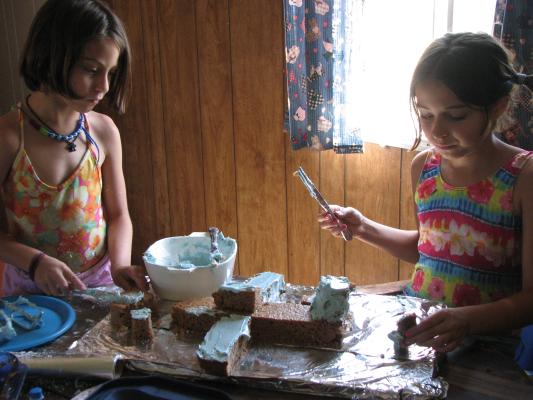 Andrea and Malia frost the cake.