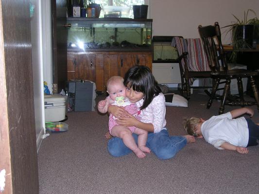 Malia holds Sarah; Noah plays on the floor.