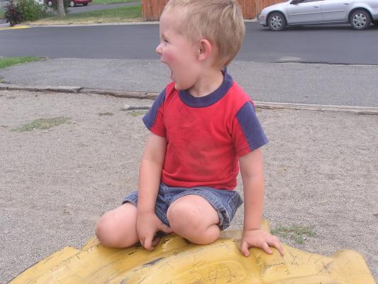 Noah making silly faces on a tire at the park.