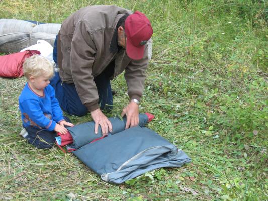 Noah helps grandpa roll up the tent.