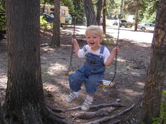 Noah sits on a swing at church camp.
