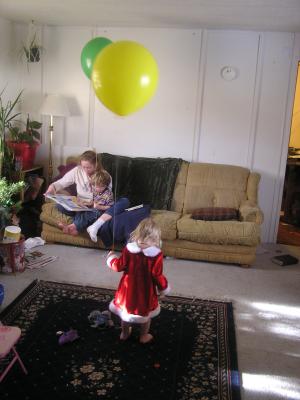 Katie reads Noah a book while Sarah plays with her big yellow balloon