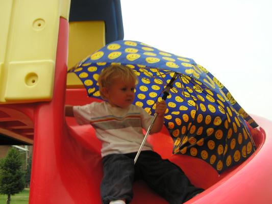 Noah plays with the umbrella at the playground.