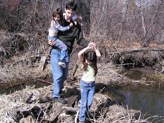 Mike helps Malia and Andrea onto the beaver dam.