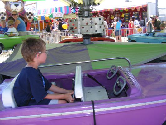 Noah drives a purple car at the fair.