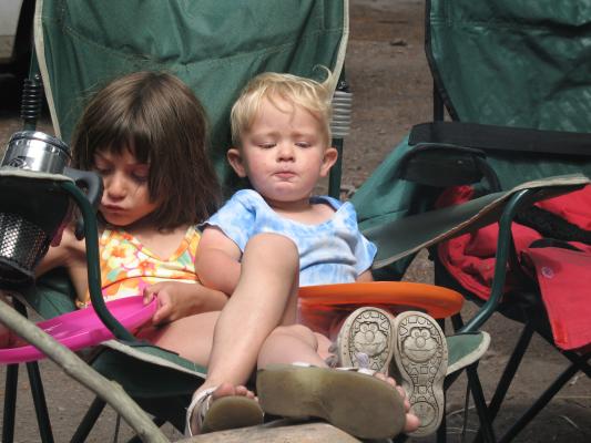 Andrea and Noah sit in a green camp chair.