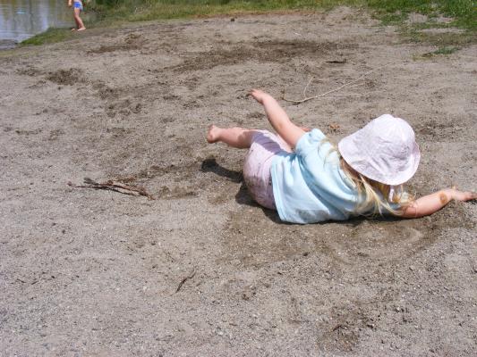 Sarah rolls in the sand and Bozeman Pond.