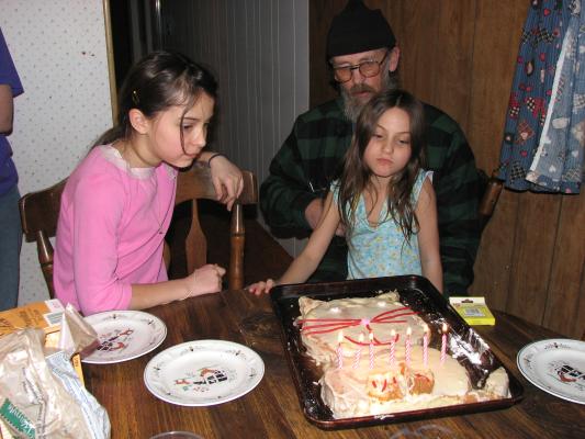 Malia watches as Andrea sits on Grandpa's lap, preparing to blow out candles