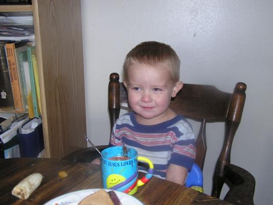 Noah enjoys some hot chocolate with a spoon.