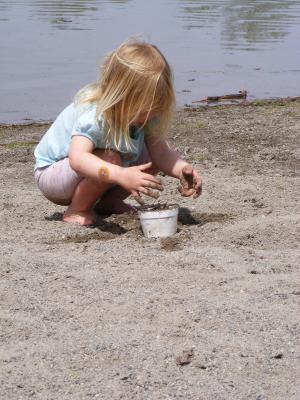 Sarah puts sand into a styrofoam cup at Bozeman Pond.