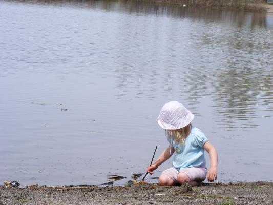 Sarah pokes a stick into the water at Bozeman Pond.