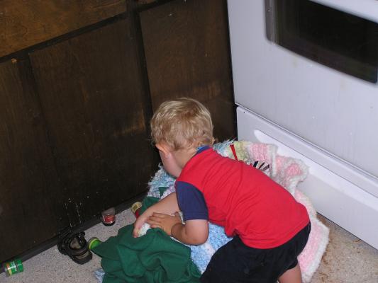 Noah plays with blankets in the kitchen.