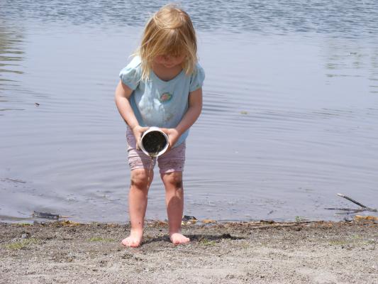 Sarah plays with a discarded styrofoam cup at Bozeman Pond.