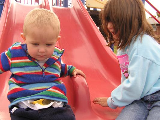 Noah and Andrea play on sldes at the playground.