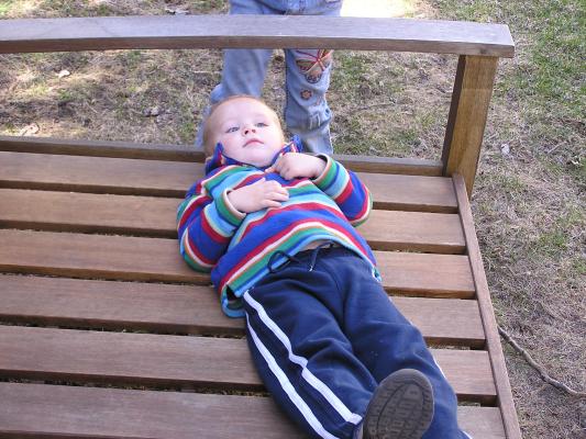 Noah lays on the wooden bench.