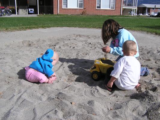 Sarah Noah and Andrea play in the sand.