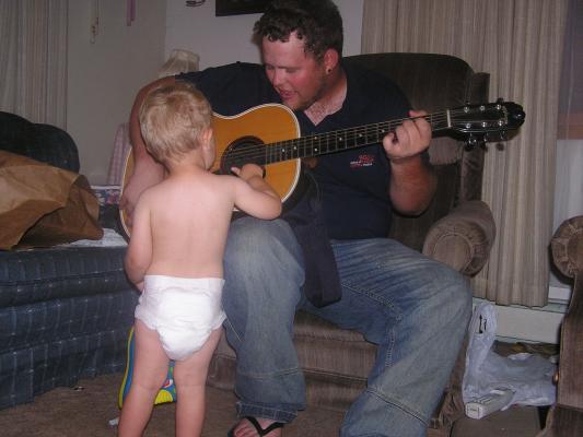 Titus teaches Noah how to play the guitar.