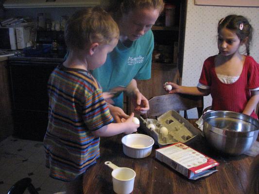 Noah and Andrea help Katie make a cake for Sarah.