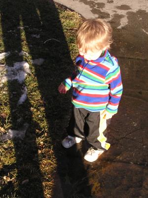 Noah plays in the puddles left by the snow.