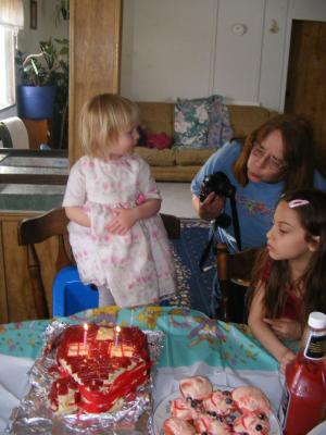 Grandma shows Sarah how to blow out the candles.