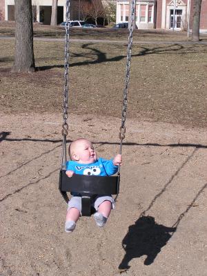 Noah in a baby swing at the park.