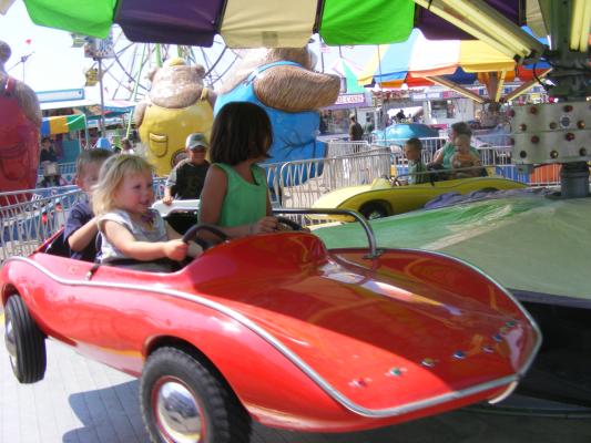 Andrea, Sarah and Noah ride a car at the fair.