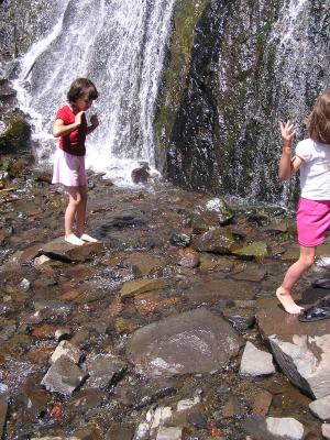 Malia and Andrea play in the waterfall.