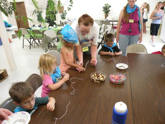 Preschoolers strings some beads at VBS.