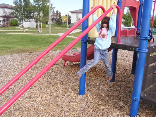 Andrea slides down poles at the playground.