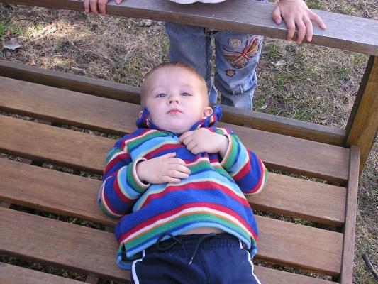 Noah lays on the wooden bench.