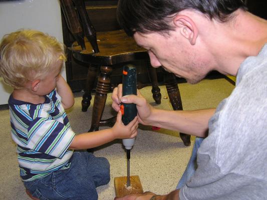 Noah and David drill a hole in a block of wood.